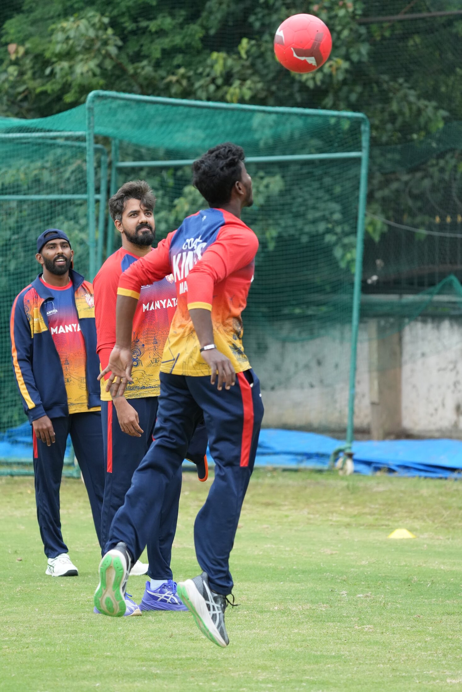 A cricket athlete completing a ball drill with Kartik Achappa watching