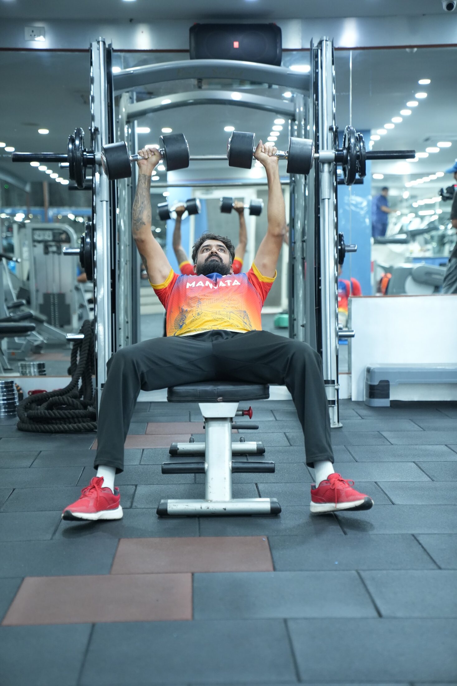 Kartik Achappa performing a dumbbell press in the gym