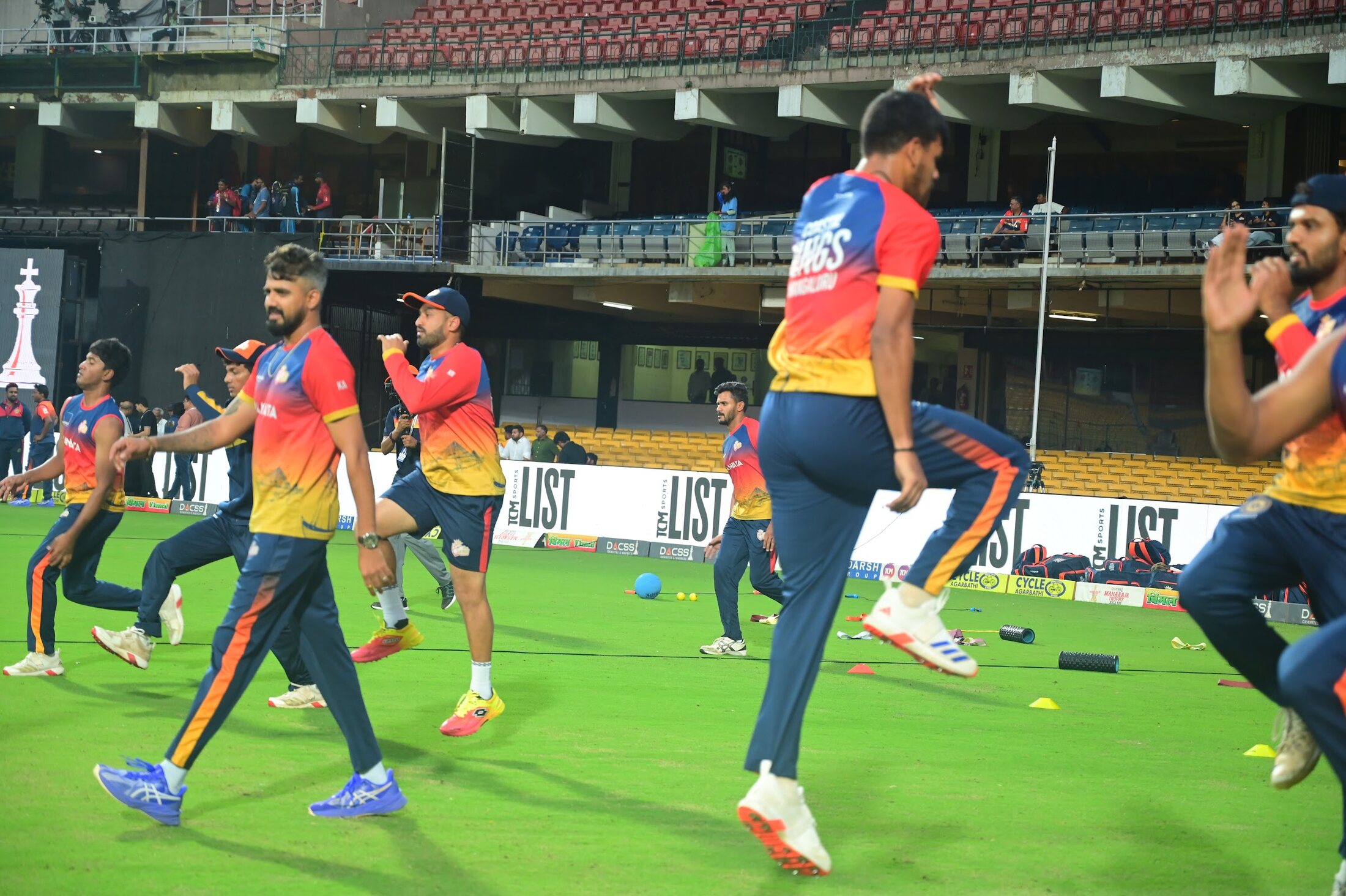 Cricketers warming up on the field under Kartik Achappa's supervision